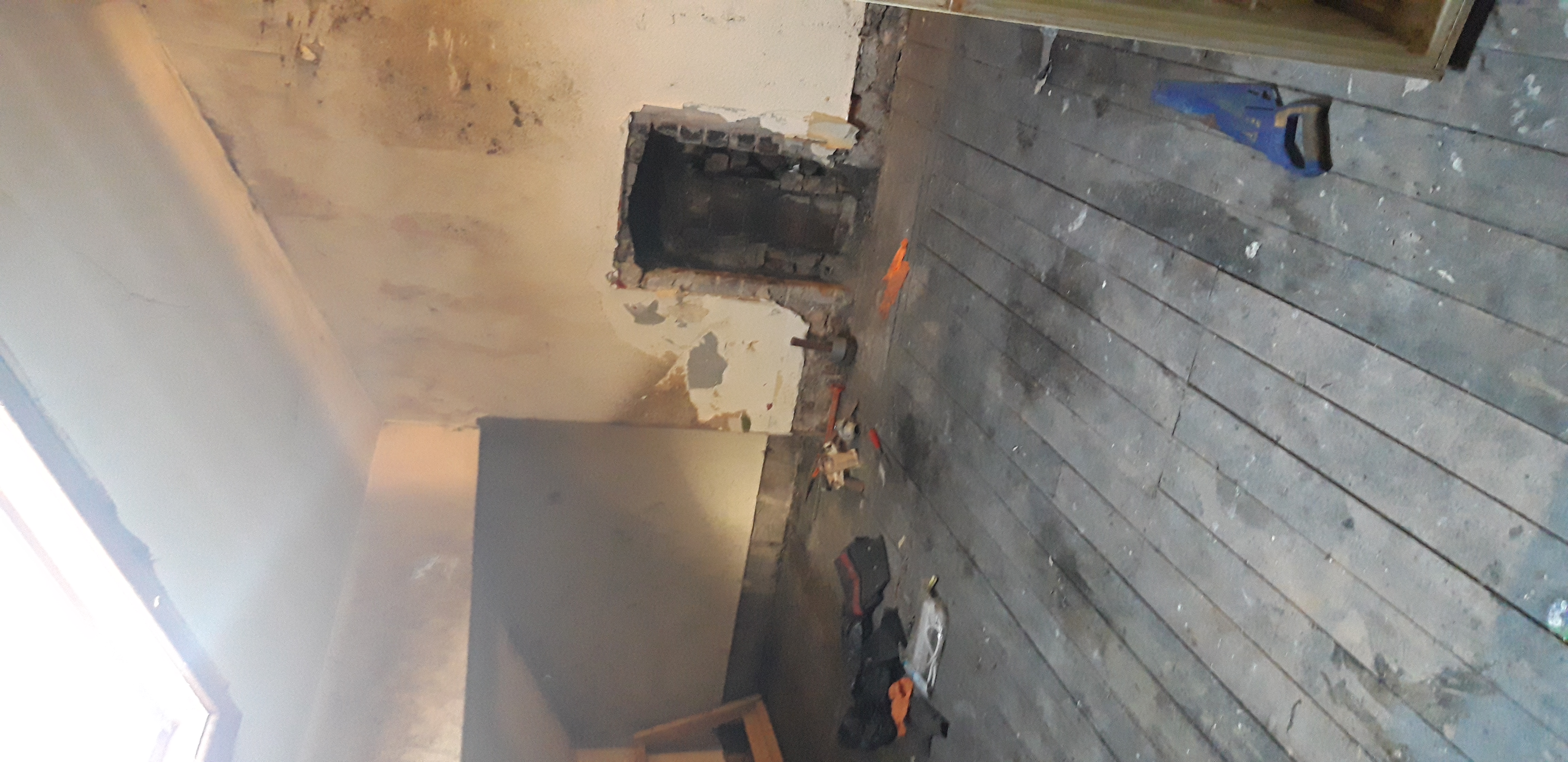 Stripped attic room with exposed brickwork and damaged flooring at acquisition
